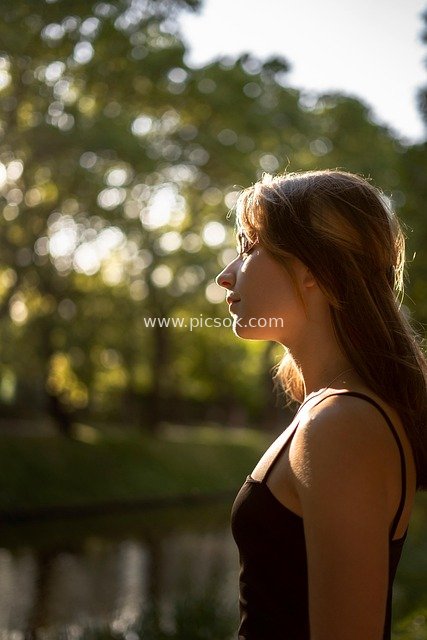 Enchanting Moment of a Young Woman Gazing Into the Distance at Sunset in the Park