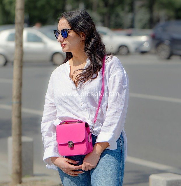 Young Woman Waiting on the Street in Casual Outfit with Pink Bag