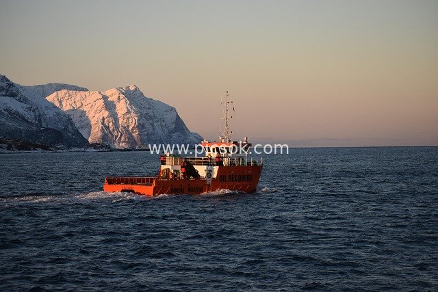Orange Rescue Boat Sailing Between Snow-Covered Mountains and Sea on the Norwegian Coast