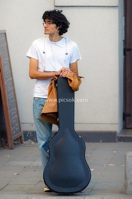 Young Boy Waiting on the Street with Guitar Case, Casual Outfit, Wearing Glasses