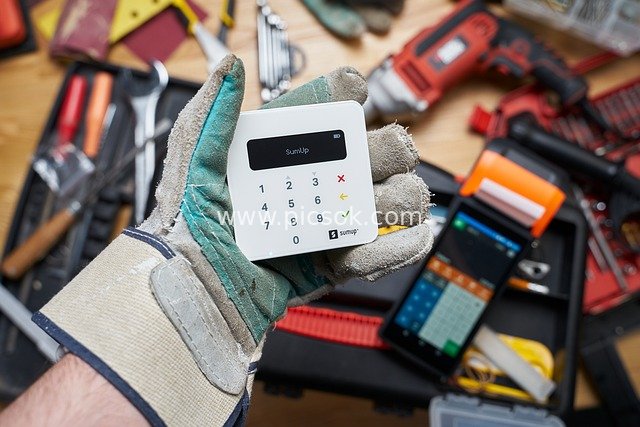 Craftsman Holding SumUp Payment Terminal: Mobile Payment Scene Near Tools