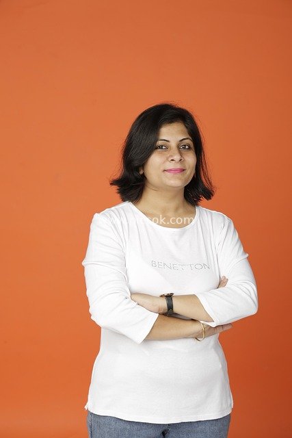 Confident Professional Woman with Arms Crossed Smiling – Business Image with Orange Background