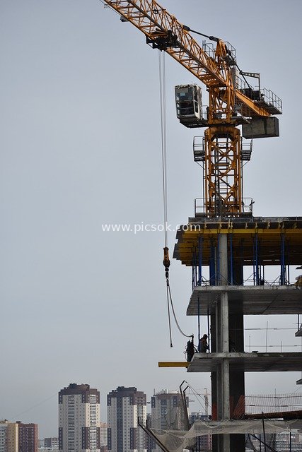 Real Shot of Tower Crane Construction and Workers Operating at Urban Construction Site