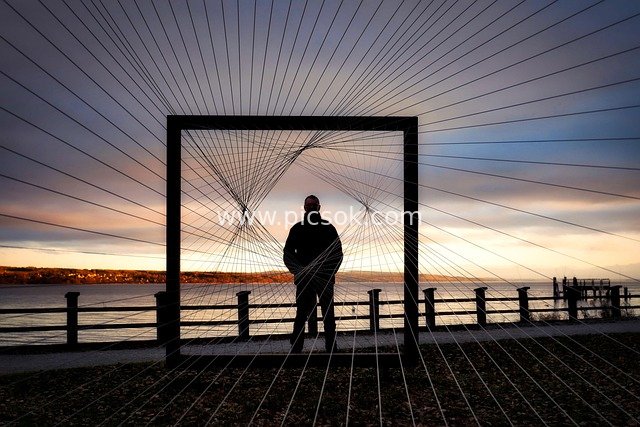 Man Gazing at Bavarian Lake at Dusk in Front of Art Installation