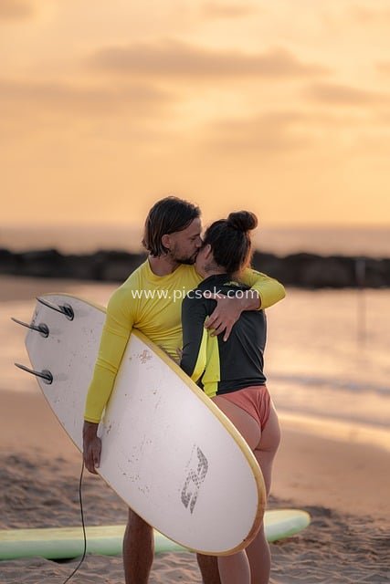 Surfing Couple Kissing at Sunset Beach: Romantic Golden Hour Scene