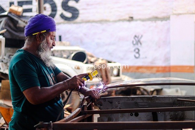Focused Work Scene of a Factory Welder Repairing a Car