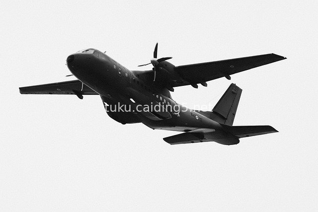 军事运输机飞行于灰白天空 黑白航空摄影