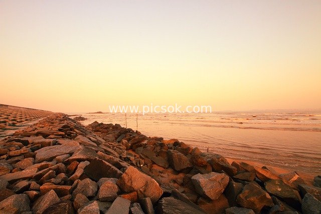 Seaside Stone Breakwater, Sandy Beach & Waves at Dusk - Natural Coastal Landscape