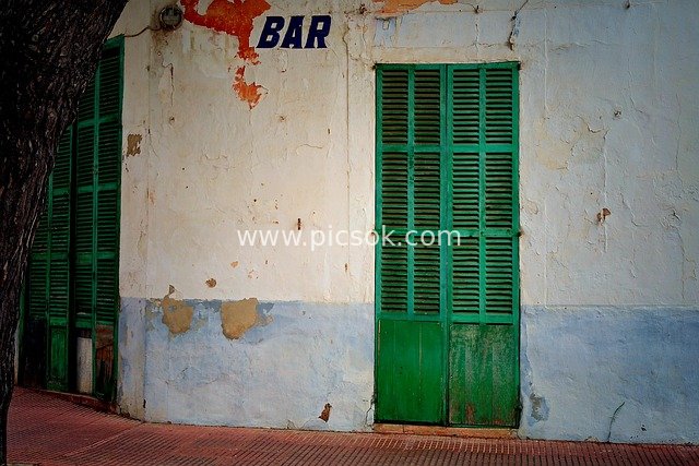 Green Wooden Door and Weathered Walls of an Abandoned Bar in Spain