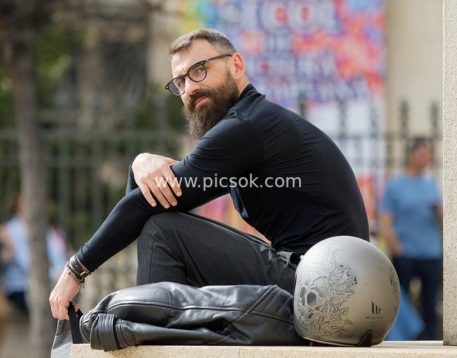 Bearded Biker with Glasses Relaxing on an Outdoor Platform