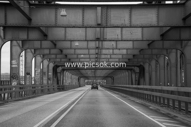 Black and White Bridge Highway Scene: Solitary Vehicle Amid Industrial Buildings