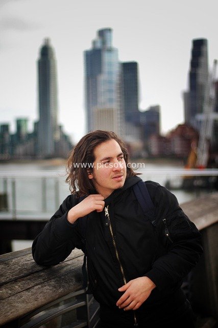 Portrait of a Casual Long-haired Man with a Backpack Against London’s Urban Skyline