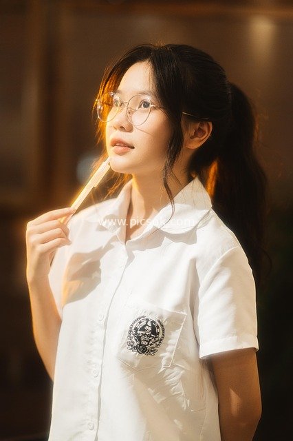 Portrait of a Cute Asian Girl in School Attire Under Warm Light