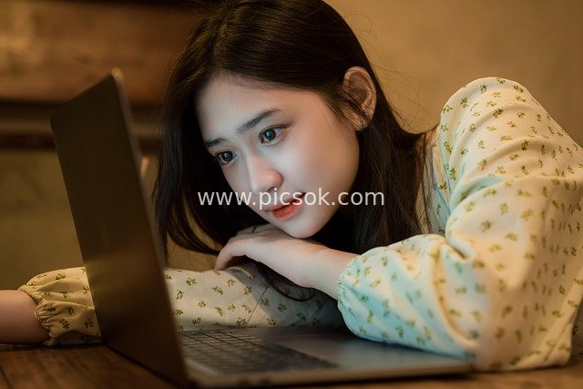 Asian Woman Working Remotely at Home, Focused on Operating Laptop