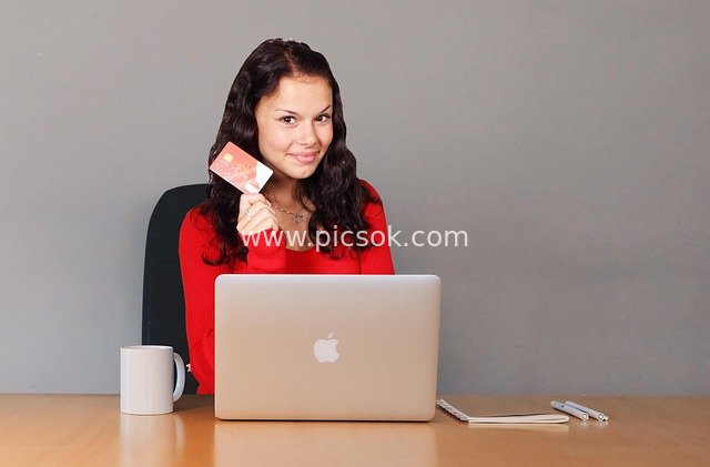 Smiling Woman Making Online Payment with Credit Card on Laptop