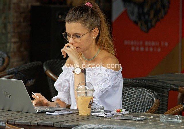 Fashionable Girl Working on an Outdoor Terrace with Coffee and Laptop