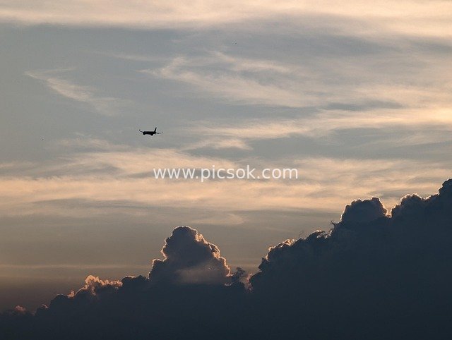日落时分天空中飞行的飞机剪影 云海美景
