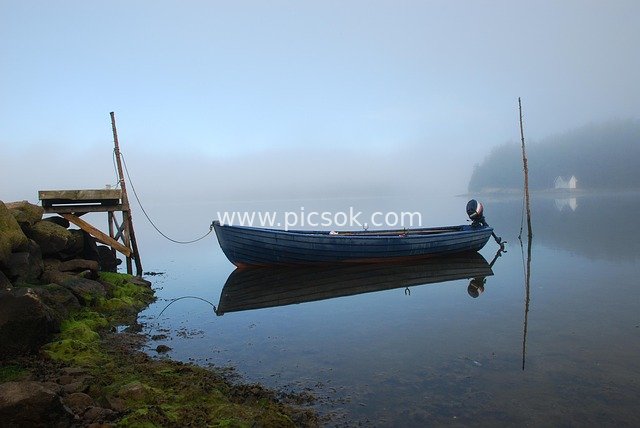 Blue Boat Quietly Moored at Stone Dock in Foggy Bohuslan Fjord at Dawn