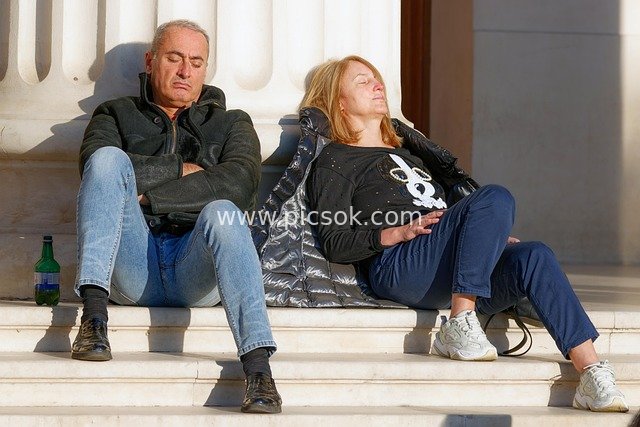 Man and Woman Resting on Sunlit Steps – Urban Relaxation Scene
