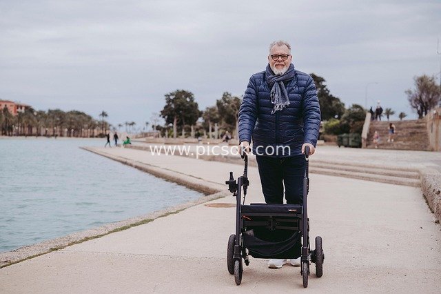 Elderly Man Walking on Seaside Promenade with a Walker