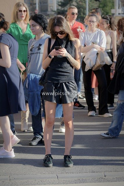Casual Urban Street Scene: Woman Checking Phone Amidst Crowds