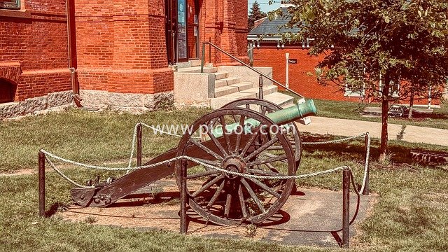 红砖墙前的古老大炮 历史军事遗迹展示