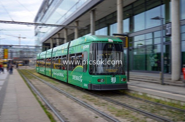 Green Tram Traveling Beside Modern Urban Buildings