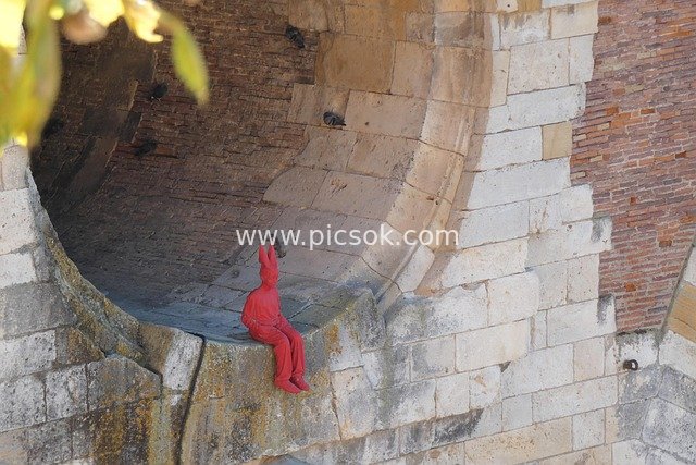 Art Installation: Red Sculpture Seated at the Entrance of a Stone Tunnel