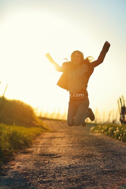 Joyful Girl Jumping on a Country Road at Sunset - A Warm Happy Moment