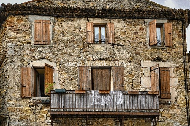 Ancient Stone Building in European Countryside: Retro House with Wooden Windows and Balcony