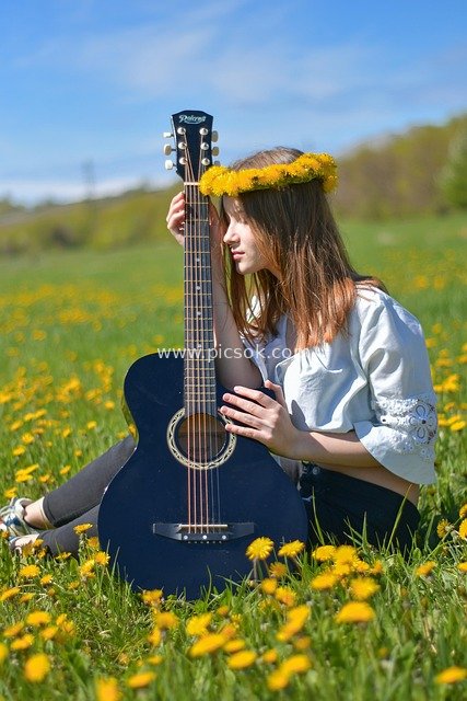 夏日蒲公英花海中抱吉他的青春少女