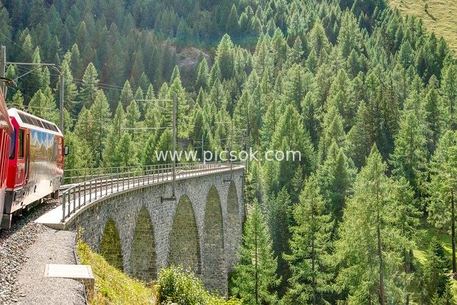 Red Train Crossing Stone Arch Viaduct in the Swiss Alps