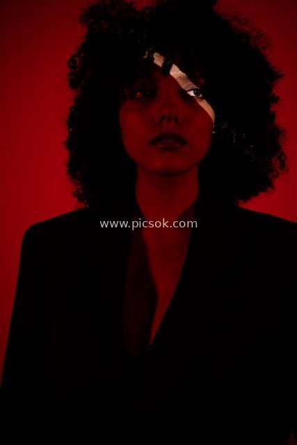 Artistic Fashion Portrait of a Curly-Haired Woman Against Red Background